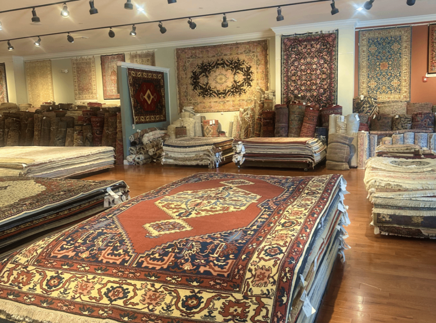 Wide showroom view with traditional oriental rugs displayed across the floor and walls